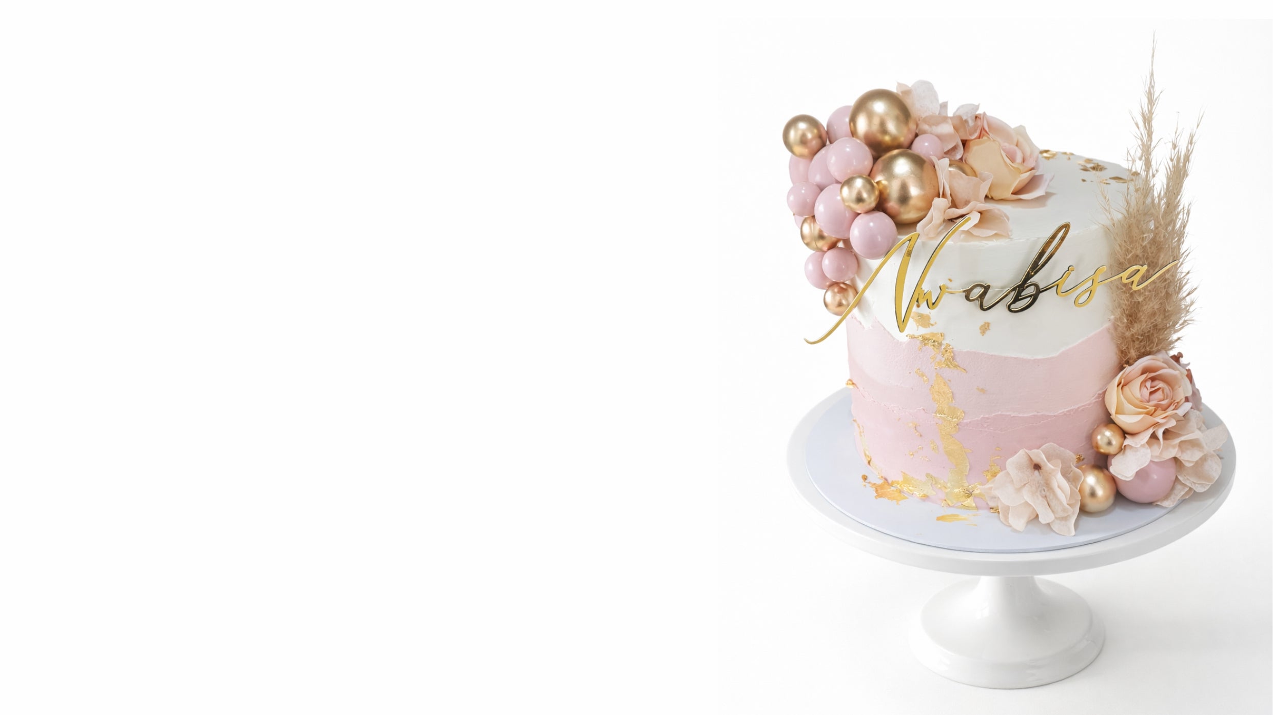 Elegant custom birthday cake with pink and gold design, floral details and name topper on white cake stand in Johannesburg