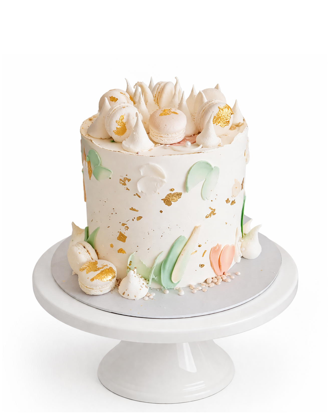 Elegant pastel cake with gold accents, macarons and meringue kisses finished in white chocolate ganache on white cake stand