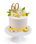 Elegant lemon themed cake with soft yellow ombre, floral decorations, macarons and gold 60 topper on white cake stand
