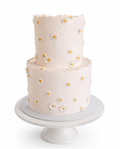Two-tier minimalist daisy cake with soft neutral tones and small floral details finished in white chocolate ganache on white cake stand